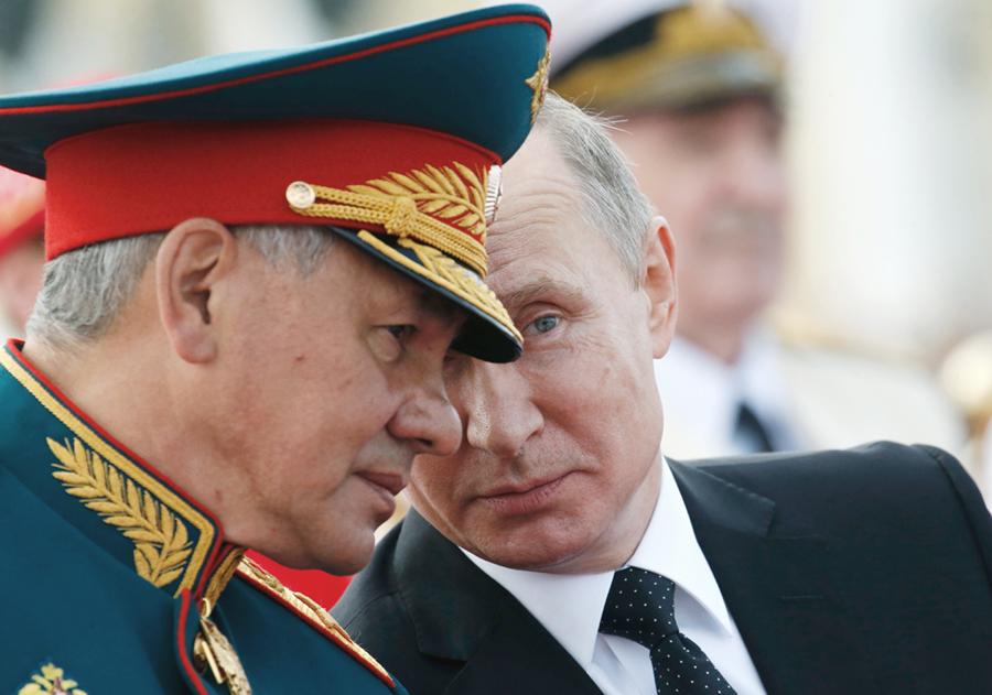 Russian President Vladimir Putin (R) speaks with Defense Minister Sergey Shoigu as they attend a ceremony for Russia’s Navy Day in Saint Petersburg on July 30. (Photo credit: Alexander Zemlianichenko/AFP/Getty Images)