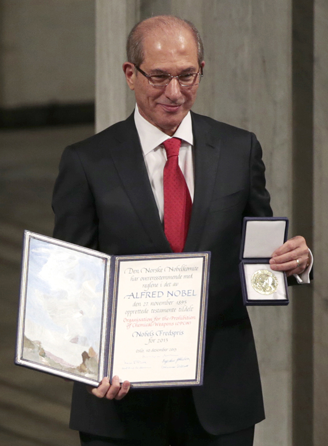 Ahmet Üzümcü (R), director-general of the Organisation for the Prohibiton of Chemical Weapons (OPCW), holds the 2013 Nobel Peace Prize at the Oslo City Hall on December 10, 2013. The Nobel was awarded to the OPCW for its extensive efforts to eliminate chemical weapons. (Photo credit: Daniel Sannum Lauten/AFP/Getty Images)