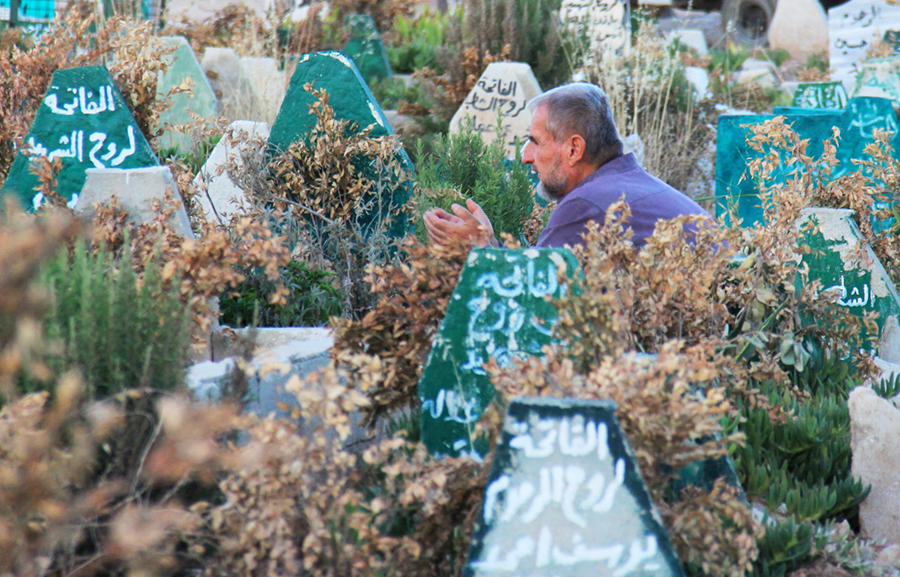 A Syrian man prays July 12 at a cemetery in Khan Sheikhoun, a rebel-held town in Idlib province, 100 days after the alleged sarin nerve-gas attack by Syrian government forces that was reported to have killed more than 90 people, including women and children. (Photo credit: Omar Haj Kadour/AFP/Getty Images)