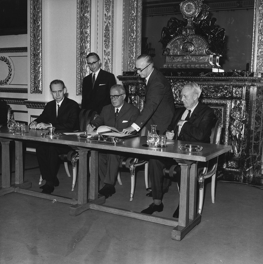 Britain’s Foreign Secretary Michael Stewart signs the treaty on the Non-Proliferation of Nuclear Weapons at Lancaster House, London, on July 1, 1968, watched by the Soviet Ambassador (left) and the US Ambassador (right).(Photo credit: Jim Gray/Keystone/Getty Images)