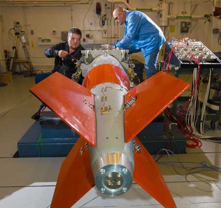 Sandia National Labratories technologists Curt Tenorio, left, and Jessie Fowler install instrumentation on a B61-12 nuclear bomb unit for a vibration and shaker-shock test. Sandia has sophisticated tests and computer models to qualify non-nuclear components under its nuclear-weapons stockpile stewardship role. (Photo: Randy Montoya/Sandia Labs)