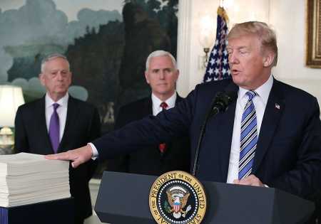 At a signing ceremony March 23, President Donald Trump gestures toward the $1.3 trillion spending bill passed by Congress, as Vice President Mike Pence and Defense Secretary Jim Mattis stand behind him. (Photo: Mark Wilson/Getty Images)