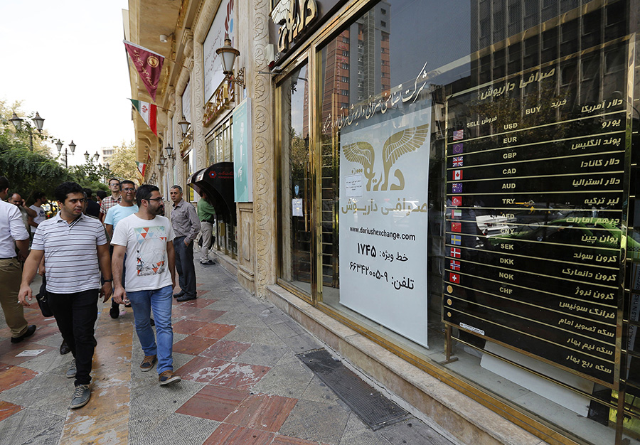 Pedestrians glace at the depressed value of the Iranian rial posted at a currency exchange shop in Tehran on August 8, the day after the reimposed U.S. sanctions took effect. (Photo: Atta Kenare/AFP/Getty Images)