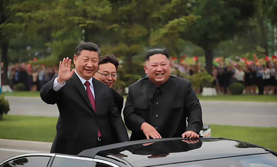 Chinese President Xi Jinping (left) and North Korean leader Kim Jong Un (right) wave during a June 21 welcome parade Xi received on his visit to Pyongyang. The two leaders focused on their talks on economic development and cooperation.  (Photo: Korean Central News Agency)