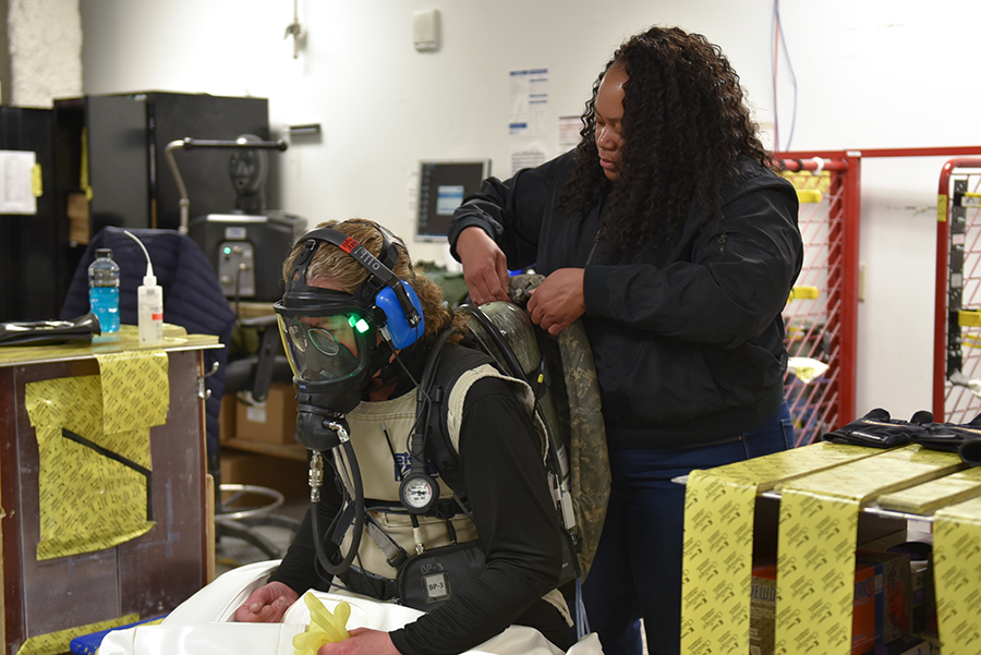 A waste operator dons safety equipment with the help of an operations support supervisor at the Pueblo Chemical Agent-Destruction Pilot Plant in February. The site has made progress in destroying its sarin-filled munitions. (Photo: PEO ACWA)