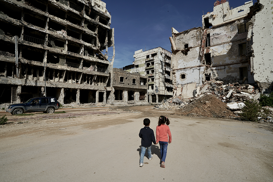 Children walk near damaged buildings in Benghazi, Libya in 2019. Conventional arms control measures in Libya, Syria, Yemen, and many other spots could support the implementation of ceasefires in those areas. (Photo: Giles Clarke/UNOCHA/Getty Images)