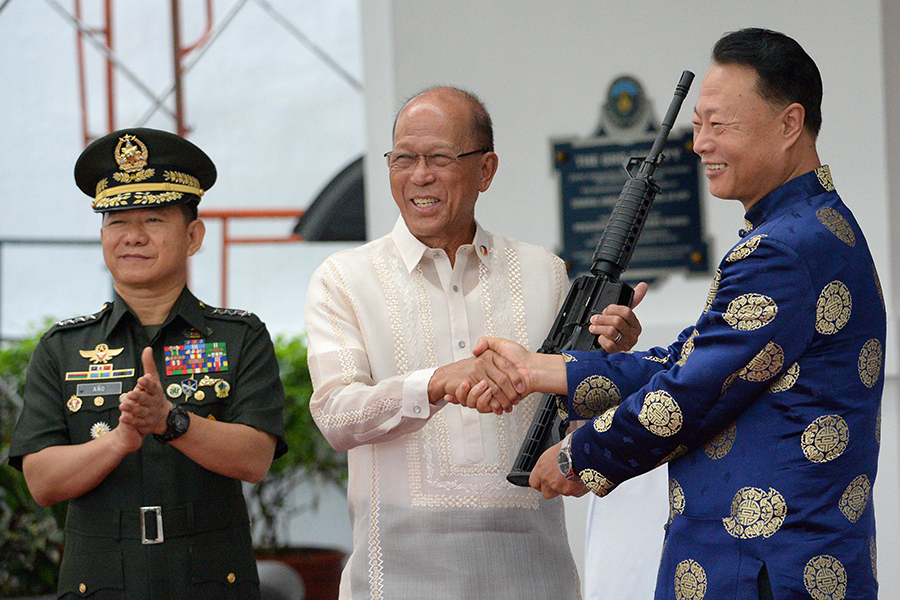 China's Ambassador to the Philippines Zhao Jinghua (right) shakes hands with Philippine Defense Secretary Delfin Lorenzana (center) as Philippine military chief Eduardo Ano applauds during a ceremony marking the delivery of 3,000 Chinese assault rifles to the Philippines in 2017. China's growing engagement with the Arms Trade Treaty could influence other countries to modify their interpretation of the treaty's rules. (Photo: Ted Aljibe/AFP/Getty Images)