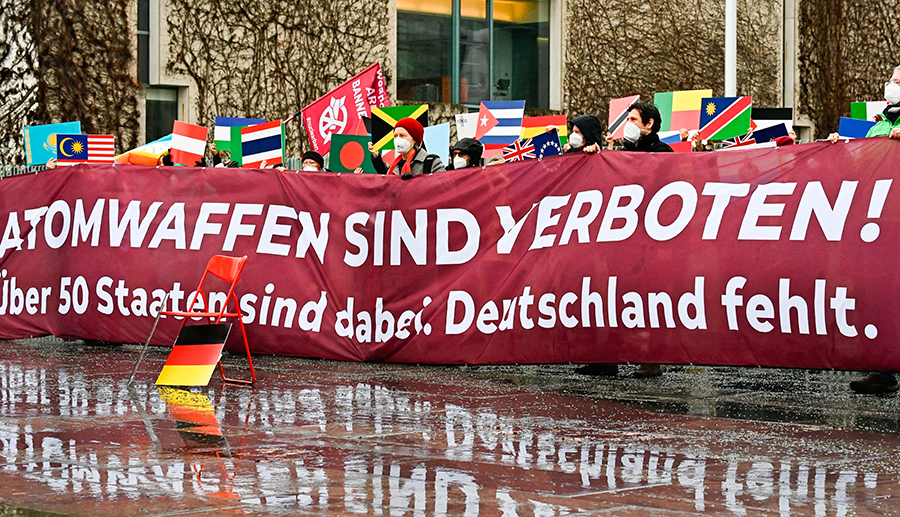 Anti-nuclear activists representing the International Campaign to Abolish Nuclear Weapons (ICAN) and other peace groups protest with the flags of 51 countries that ratified the UN Treaty to Prohibit Nuclear Weapons and a banner reading “Nuclear weapons are forbidden! More than 50 states joined. Germany didn't” in Berlin on January 22, 2021. (Photo by TOBIAS SCHWARZ/AFP via Getty Images)