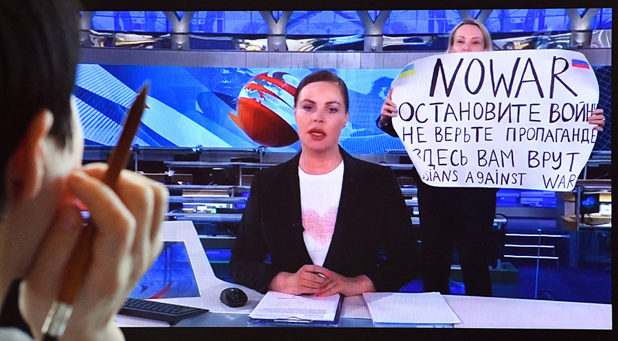 A woman looks at a computer screen showing a dissenting Russian Channel One employee, Marina Ovsyannikova, entering an on-air TV studio during Russia's most-watched evening news broadcast on March 15. The protester held a poster reading "No War" and condemning Moscow's military action in Ukraine. (Photo by AFP via Getty Images)