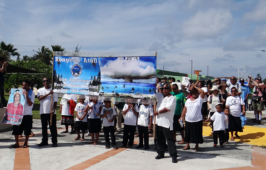 Islanders from Rongelap Atoll in The Marshall Islands, which was damaged by U.S. nuclear testing, march while holding banners marking the 60th anniversary of the Bravo hydrogen bomb test at Bikini Atoll in Majuro on March 1, 2014. The Marshallese have long called on the United States to resolve the "unfinished business" of its nuclear testing legacy in the western Pacific nation.  (Photo by Isaac Marty/AFP via Getty Images)