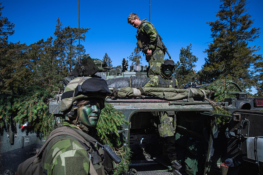 As Finland and Sweden began taking formal steps to join NATO, Swedish Army troops, here camouflaging an armoured vehicle, participated in military exercises on the Swedish island of Gotland in May. (Photo by JONATHAN NACKSTRAND/AFP via Getty Images) 