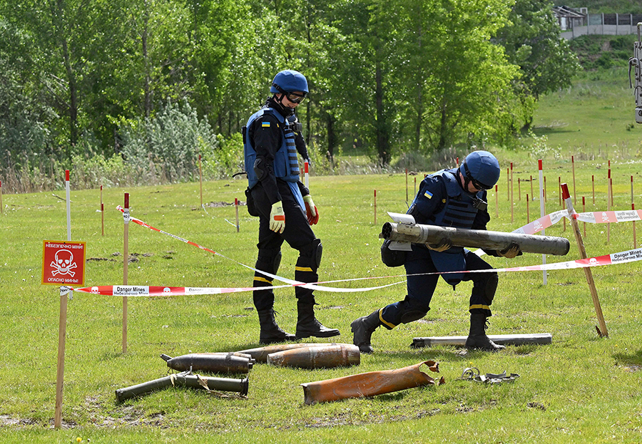 Ukrainian deminers collect unexploded material during a demining operation in Horenka village in the Kyiv region in May as Russia pressed its war in Ukraine.  (Photo by Sergei Supinsky/AFP via Getty Images)