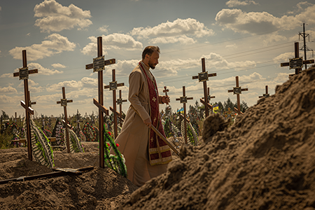 A priest prays on fresh graves of unidentified civilians killed by Russian troops on September 2, 2022 in Bucha, Ukraine. Author Christopher F. Chyba writes that it is too easy for a “bloodless discussion of nuclear deterrence to lose sight of the scale of human suffering implied in that discussion.” (Photo by Serhiy Morgunov/Global Images Ukraine via Getty Images)
