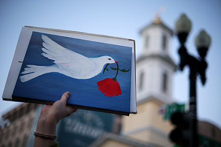 An anti-war demonstrator holds up a sign with a symbol of peace near the White House on April 7, 2026, in Washington, D.C. (Photo by Alex Wong/Getty Images)