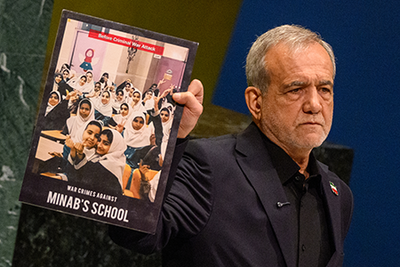 Iranian President Masoud Pezeshkian, addressing the UN General Assembly in September, displays a photo of students at a school that was attacked during U.S. missile strikes on the country. (Photo by Alexi J. Rosenfeld/Getty Images)