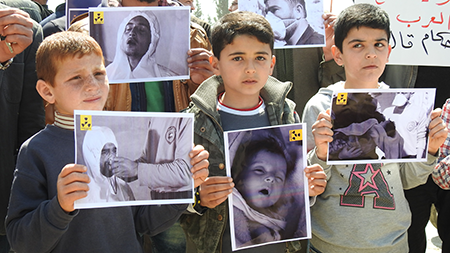 Survivors of a chemical gas attack gather to protest the regime of Syrian President Bashar al-Assad at the Khan Shaykhun town square in Idlib, Syria, in April 2017. With Assad now ousted, the successor government has begun destroying the country’s chemical weapons arsenal in 2026. (Photo by Firas Faham/Anadolu Agency/Getty Images)