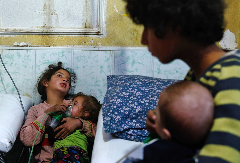 A Syrian girl holds an oxygen mask over the face of an infant at a make-shift hospital following a reported gas attack on Douma, January 22, 2018. Since the beginning of the war, the government of Bashar al-Assad has been repeatedly accused by UN investigators of using chlorine gas or sarin gas in sometimes lethal chemical attacks.  (Photo: HASAN MOHAMED/AFP via Getty Images)