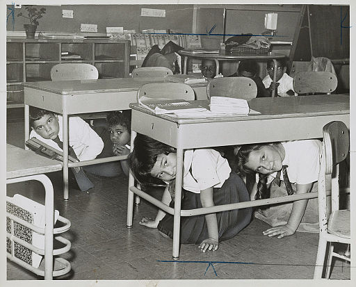 Students at a public school in Brooklyn practicing taking cover under their desks in a 1962 drill. (Photo by Walter Albertin, Wikimedia Commons)